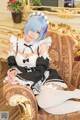 A woman in a maid outfit sitting on a chair.