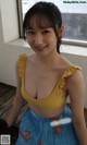 A woman in a yellow top and blue skirt posing for a picture.