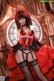 A woman in a red and black corset and stockings posing for a picture.