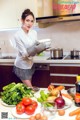 A woman standing in a kitchen holding a bowl of vegetables.