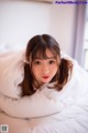 A woman laying on top of a bed covered in white sheets.