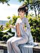 A woman in a white kimono sitting on a bench.