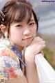 A young woman in a kimono leaning on a railing.