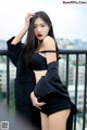 A woman in a black top and shorts posing on a balcony.